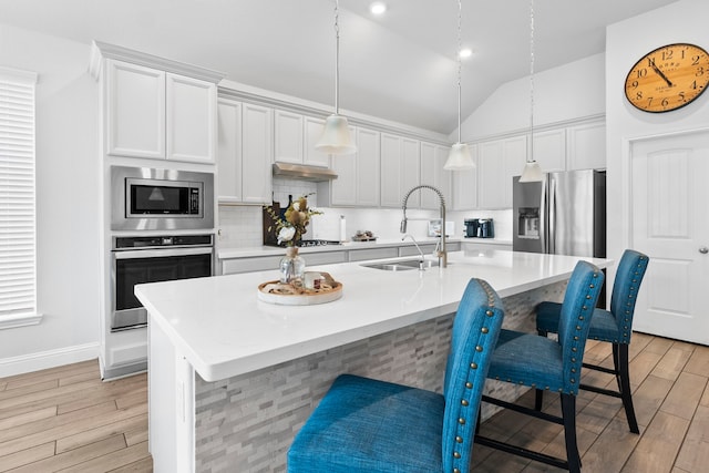 kitchen featuring appliances with stainless steel finishes, sink, a center island with sink, and a kitchen breakfast bar