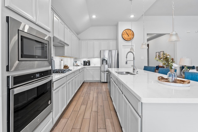 kitchen with sink, white cabinets, stainless steel appliances, a center island with sink, and light wood-type flooring