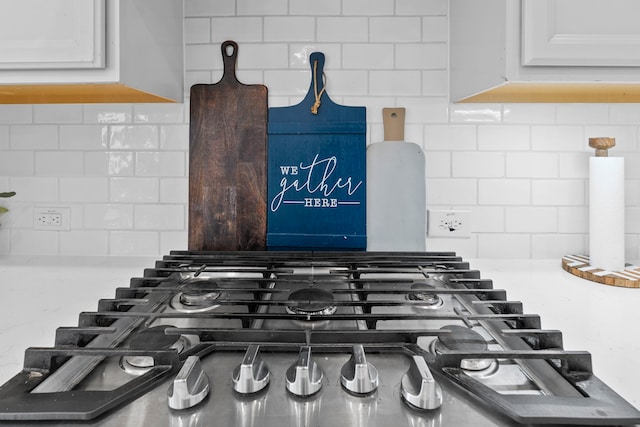 interior details with tasteful backsplash, cooktop, and white cabinets