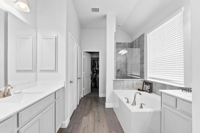 bathroom featuring hardwood / wood-style flooring, vanity, separate shower and tub, and lofted ceiling