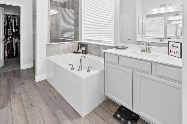 bathroom with hardwood / wood-style flooring, vanity, and a tub