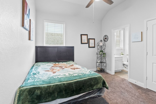 carpeted bedroom with multiple windows, lofted ceiling, ceiling fan, and ensuite bathroom