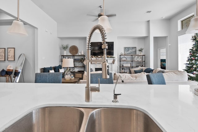 kitchen featuring ceiling fan, light stone countertops, sink, and hanging light fixtures