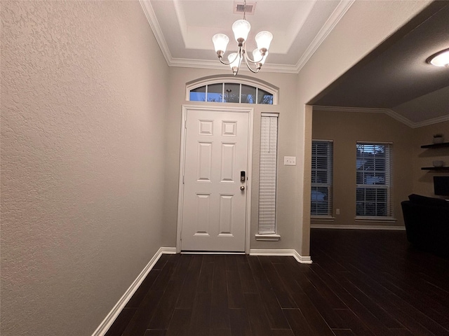 entryway featuring a tray ceiling, a notable chandelier, crown molding, and dark hardwood / wood-style flooring