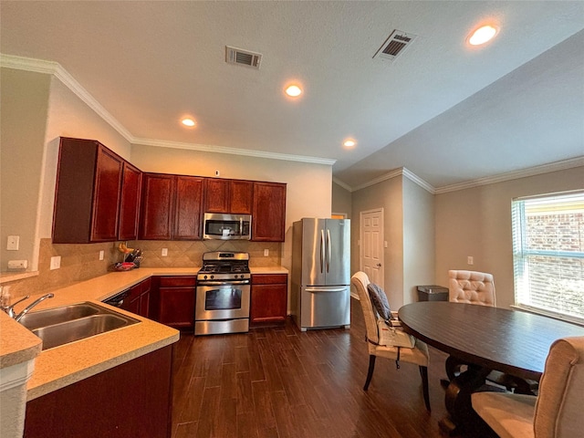 kitchen with appliances with stainless steel finishes, sink, decorative backsplash, ornamental molding, and dark wood-type flooring