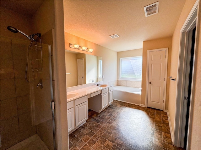 bathroom featuring plus walk in shower, vanity, and a textured ceiling