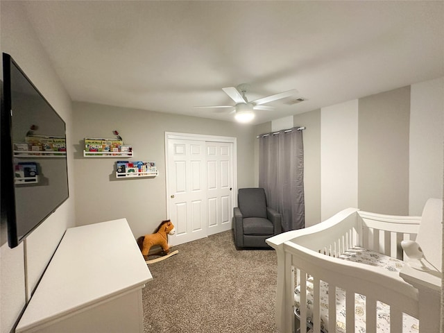 carpeted bedroom featuring a crib, ceiling fan, and a closet