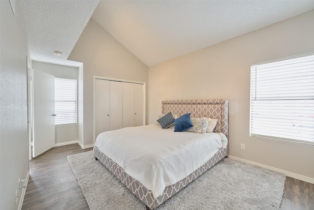 bedroom featuring a closet, vaulted ceiling, hardwood / wood-style floors, and a textured ceiling