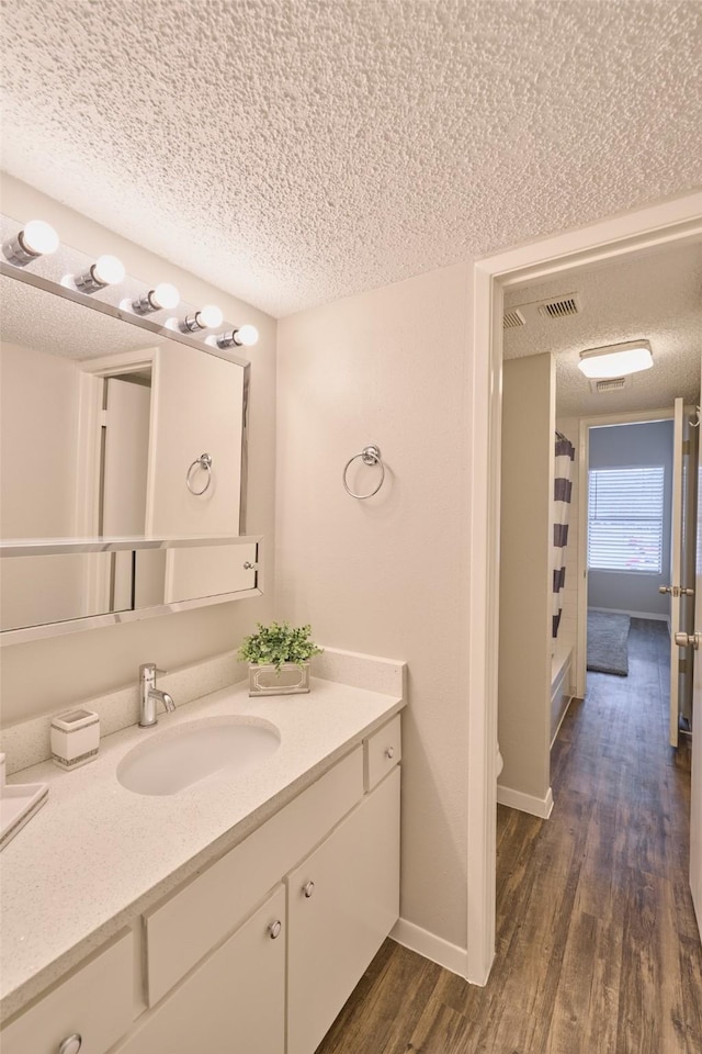 bathroom with vanity, curtained shower, wood-type flooring, and a textured ceiling