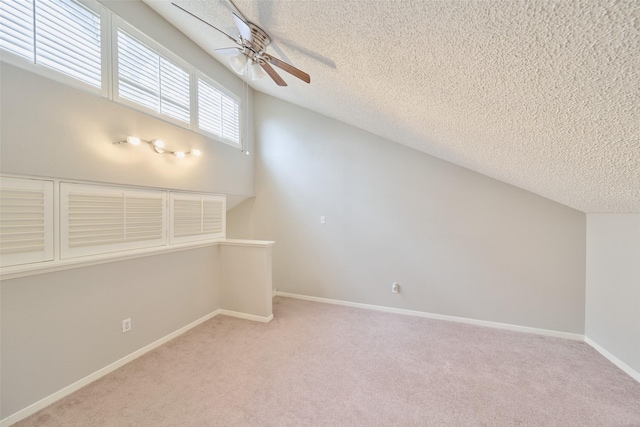 additional living space featuring light carpet, a textured ceiling, vaulted ceiling, and ceiling fan