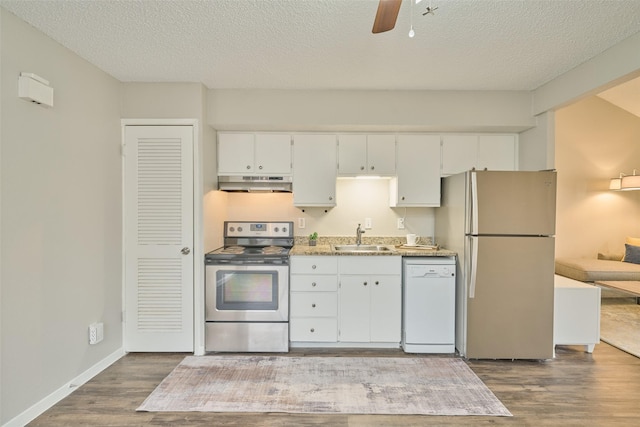 kitchen with sink, dark wood-type flooring, appliances with stainless steel finishes, white cabinetry, and light stone countertops