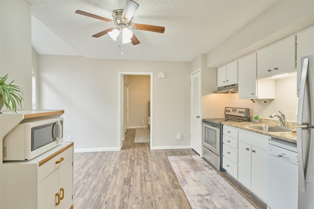 kitchen with appliances with stainless steel finishes, sink, light wood-type flooring, white cabinets, and a textured ceiling