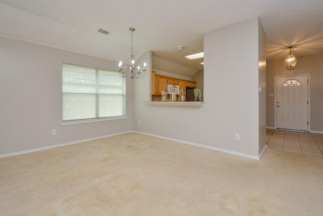 carpeted spare room with lofted ceiling and an inviting chandelier