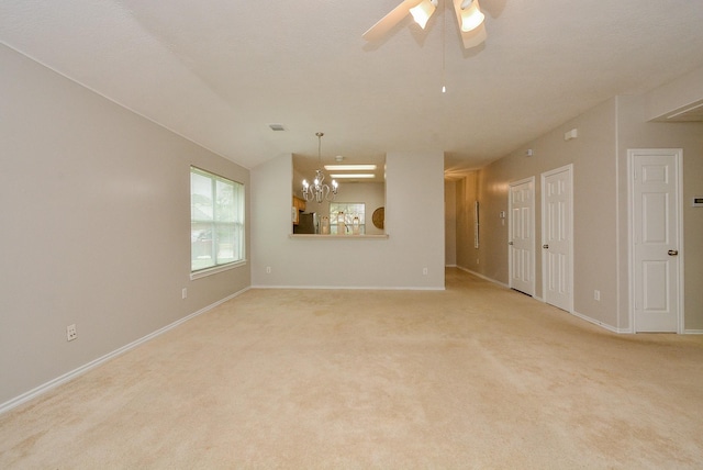 empty room featuring ceiling fan with notable chandelier and light colored carpet