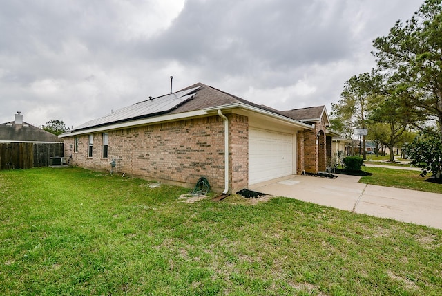 view of side of property featuring central AC unit, a garage, a lawn, and solar panels