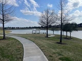 surrounding community featuring a water view and a lawn