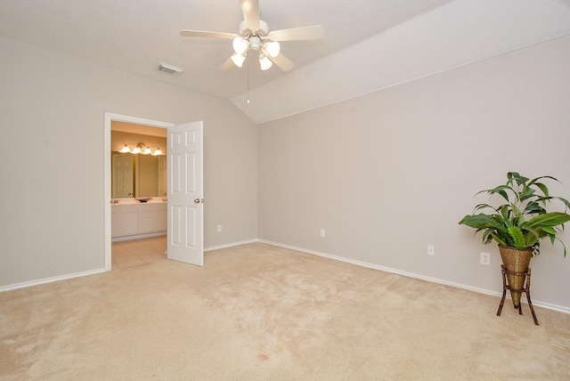 unfurnished bedroom with vaulted ceiling, light colored carpet, ceiling fan, and ensuite bathroom