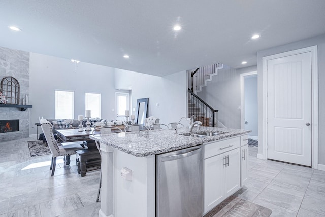 kitchen featuring sink, white cabinetry, a kitchen island with sink, a kitchen bar, and stainless steel dishwasher