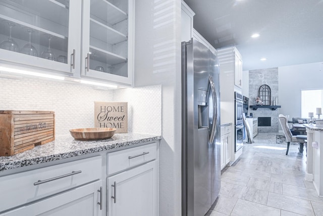 kitchen featuring stainless steel appliances, tasteful backsplash, white cabinets, and light stone counters