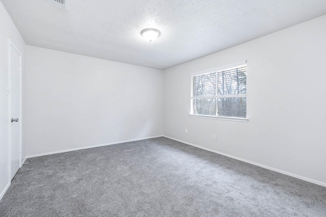 spare room featuring a textured ceiling and dark carpet