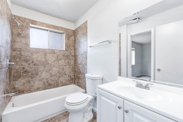 full bathroom with vanity, tiled shower / bath, toilet, and a textured ceiling