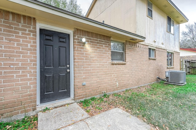 doorway to property featuring central AC unit and a lawn