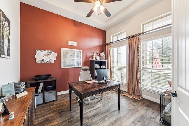 home office featuring dark wood-type flooring, a raised ceiling, and ceiling fan