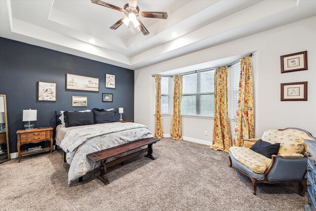 carpeted bedroom featuring ceiling fan and a tray ceiling