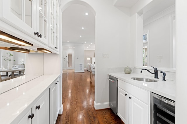 bar with sink, white cabinets, wine cooler, light stone countertops, and dark wood-type flooring