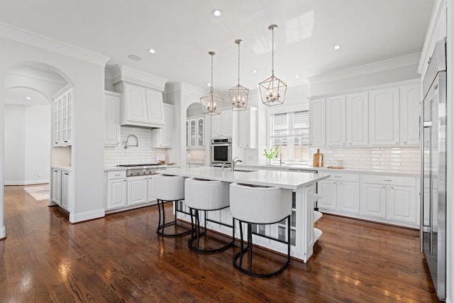 kitchen featuring dark wood-type flooring, a breakfast bar area, a center island with sink, and white cabinets