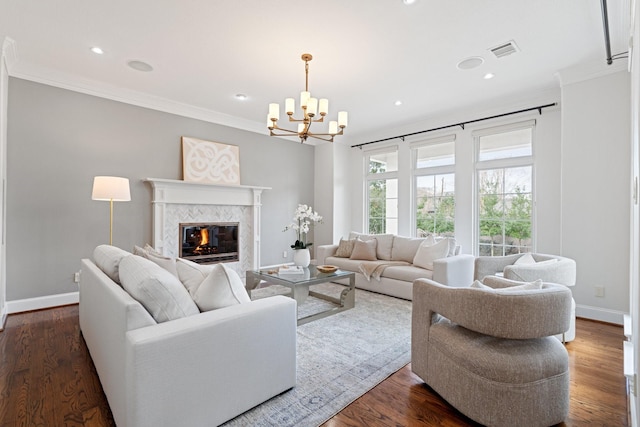 living room with a notable chandelier, crown molding, a tile fireplace, and dark hardwood / wood-style floors