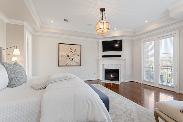 bedroom with hardwood / wood-style flooring, ornamental molding, a raised ceiling, and access to outside