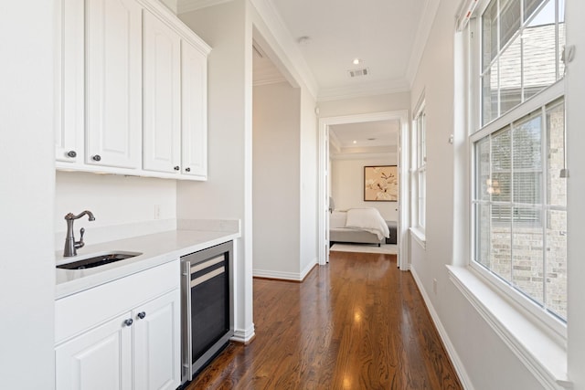 interior space featuring sink, ornamental molding, white cabinets, dark hardwood / wood-style flooring, and beverage cooler