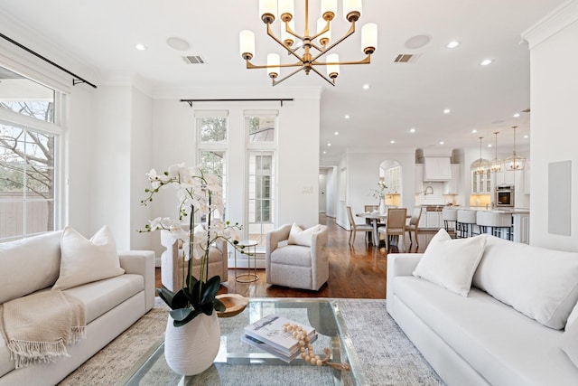 living room with crown molding, a chandelier, and hardwood / wood-style flooring