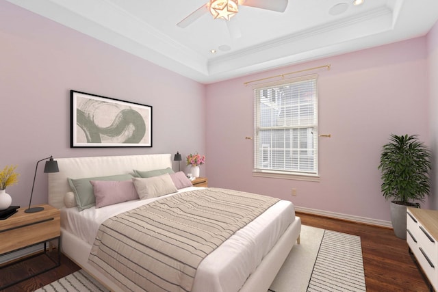 bedroom featuring dark hardwood / wood-style flooring, a tray ceiling, ornamental molding, and ceiling fan