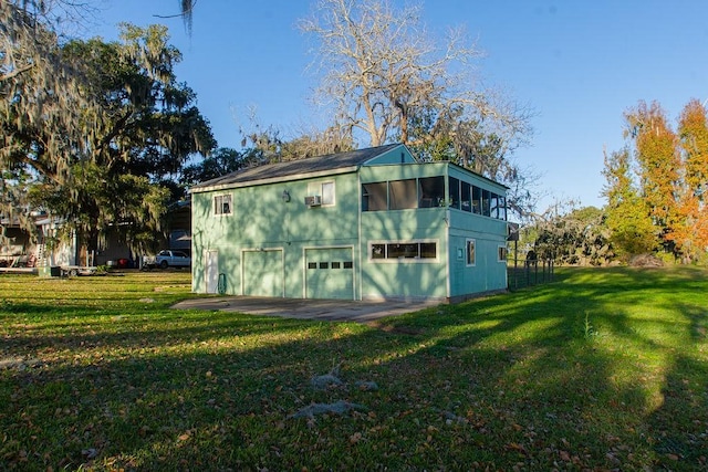 view of outbuilding featuring a garage, a lawn, and a sunroom