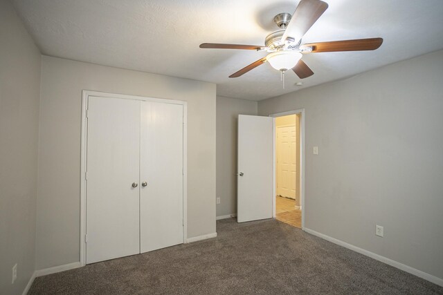 unfurnished bedroom featuring ceiling fan, carpet flooring, and a closet