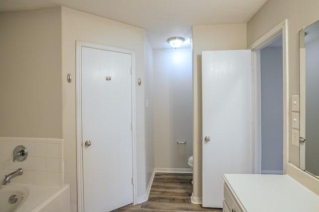 bathroom with vanity, wood-type flooring, a bath, and toilet