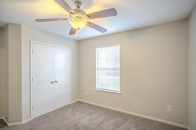 unfurnished bedroom with ceiling fan, a closet, and light carpet