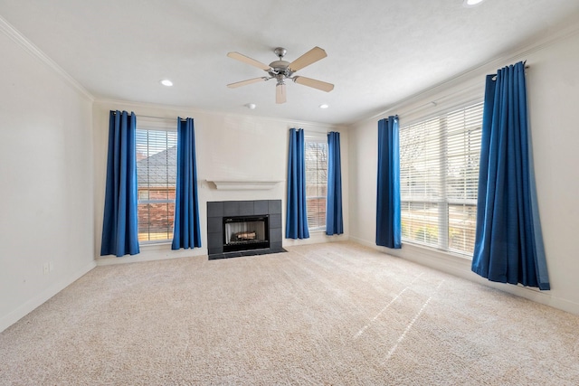 unfurnished living room with a tile fireplace, crown molding, light carpet, and ceiling fan