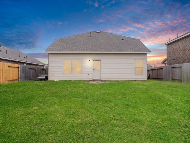 back house at dusk featuring a yard