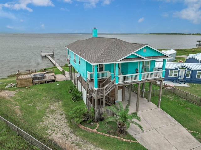 view of front facade featuring a water view, a carport, a porch, and a front lawn