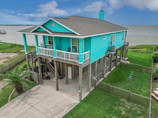 rear view of house featuring a porch, a lawn, cooling unit, a carport, and a water view