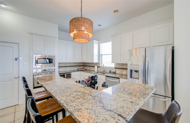 kitchen with white cabinetry, appliances with stainless steel finishes, sink, and hanging light fixtures