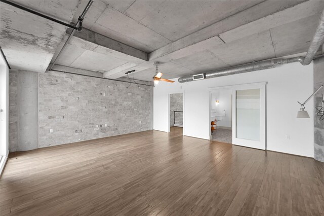 spare room featuring brick wall, hardwood / wood-style floors, and ceiling fan