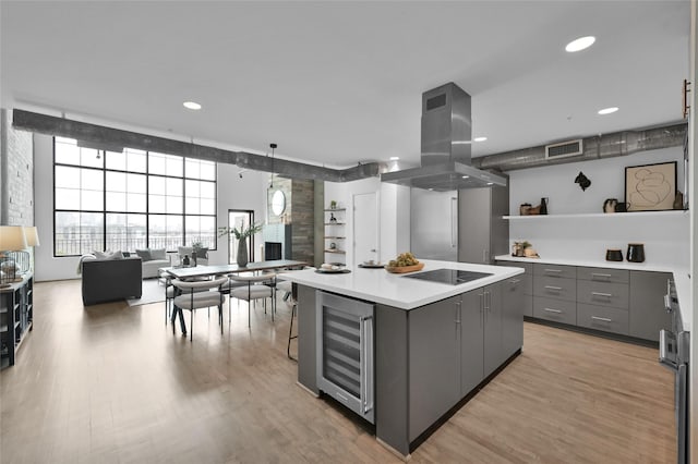 kitchen with gray cabinets, island range hood, beverage cooler, a center island, and black electric cooktop