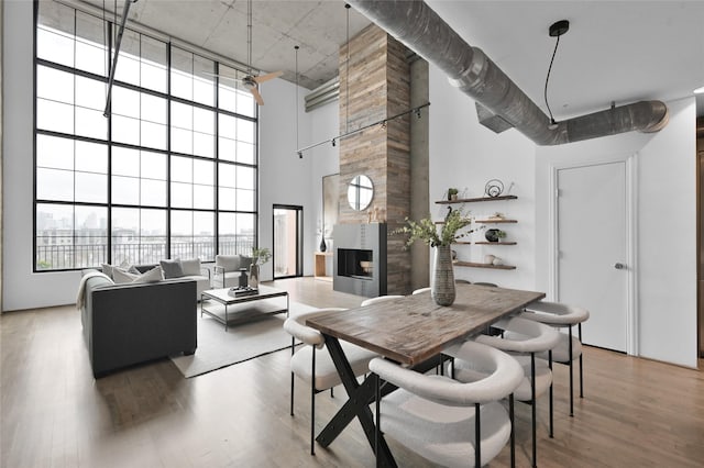 dining area featuring hardwood / wood-style flooring, a towering ceiling, and a fireplace