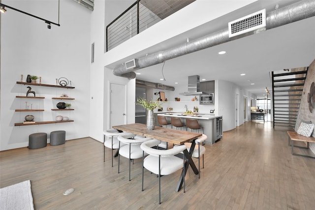 dining space with light hardwood / wood-style flooring and a high ceiling