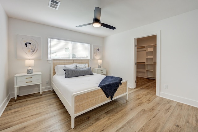 bedroom featuring a closet, a spacious closet, ceiling fan, and light hardwood / wood-style flooring