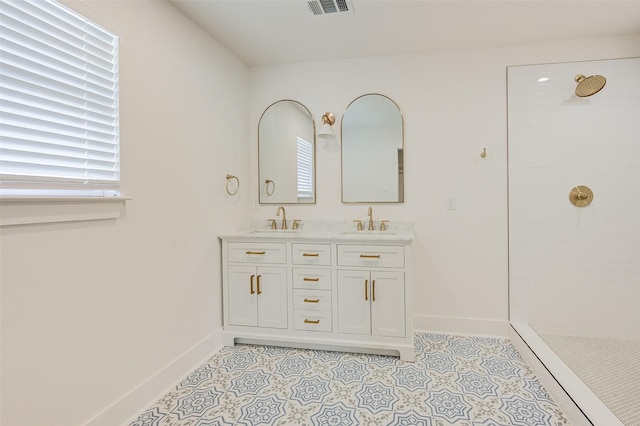 bathroom with a tile shower, vanity, a wealth of natural light, and tile patterned floors